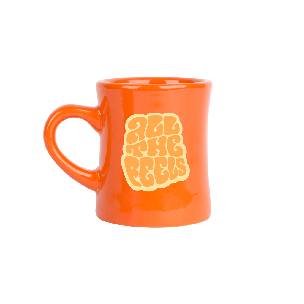 Orange mug with yellow text that reads all the feels on a white background