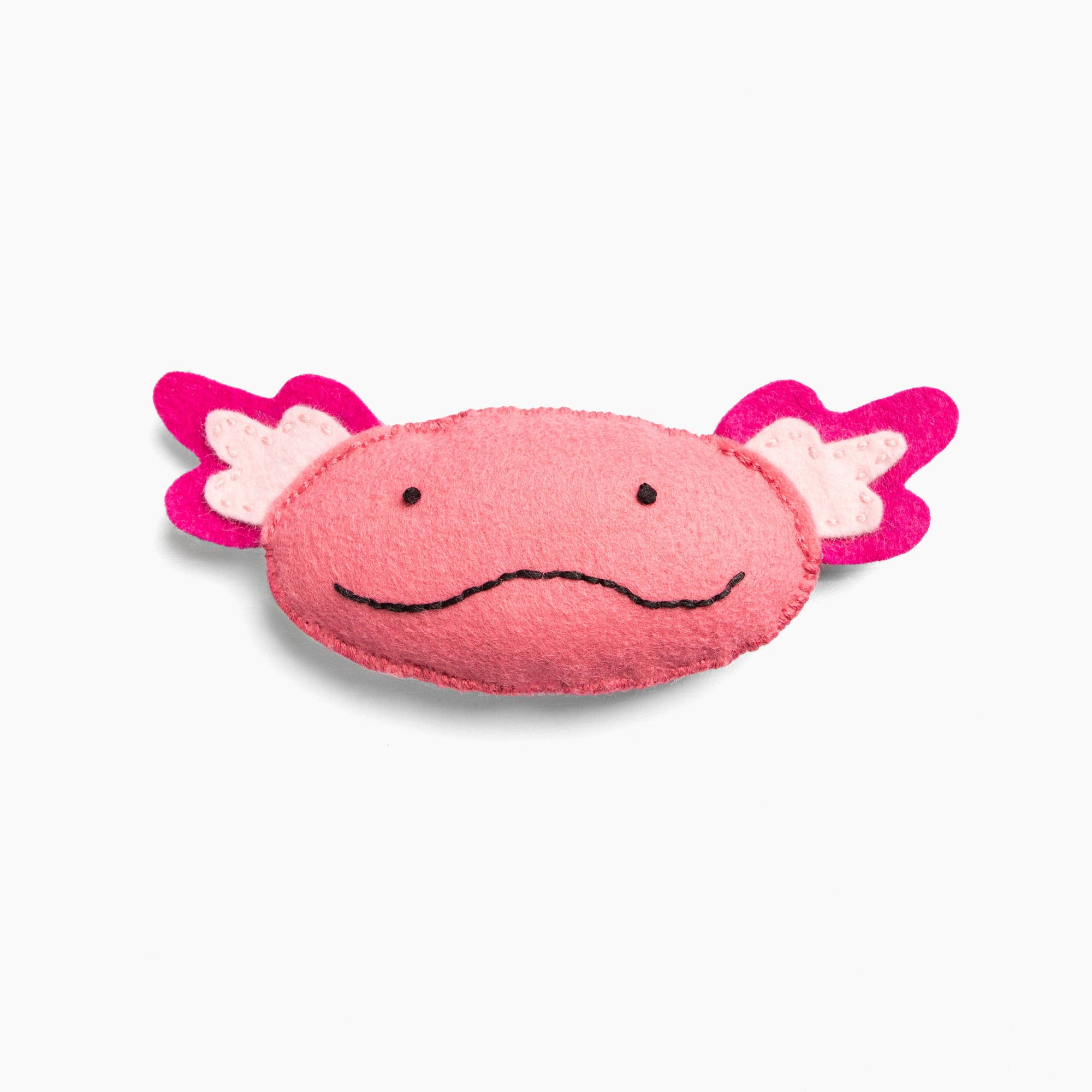 Pink axolotl-shaped felt toy with pink ears on a white background