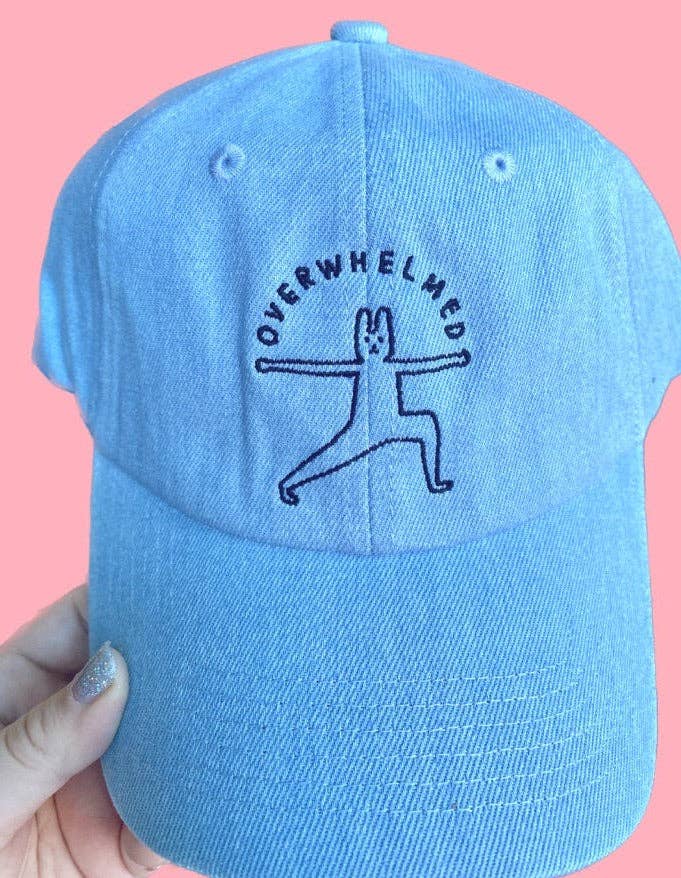 Light blue cap with 'Overwhelmed' yoga pose design on a pink background 2
