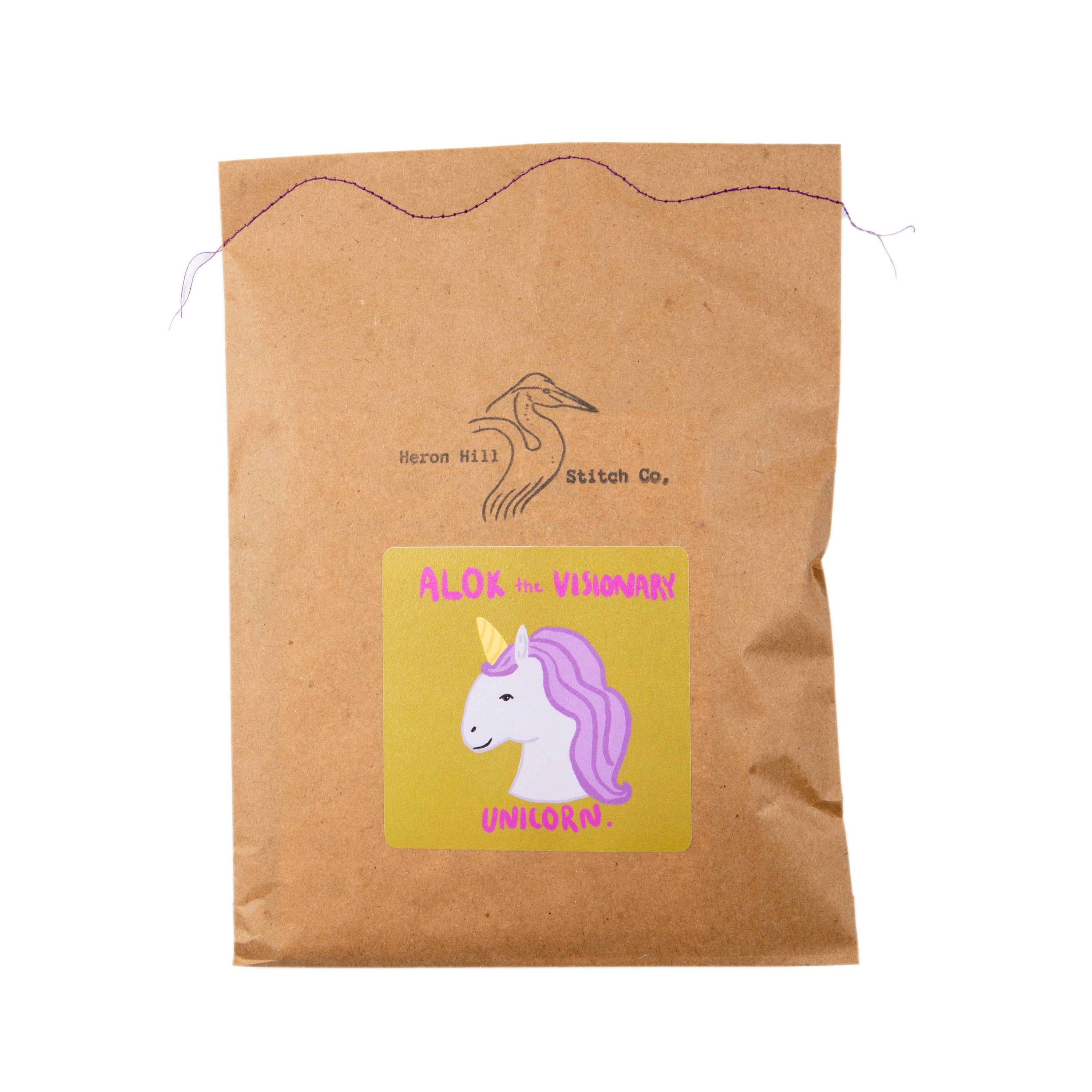 Kraft paper bag with a unicorn label and Hezon Hill Stitch Co. branding on a white background