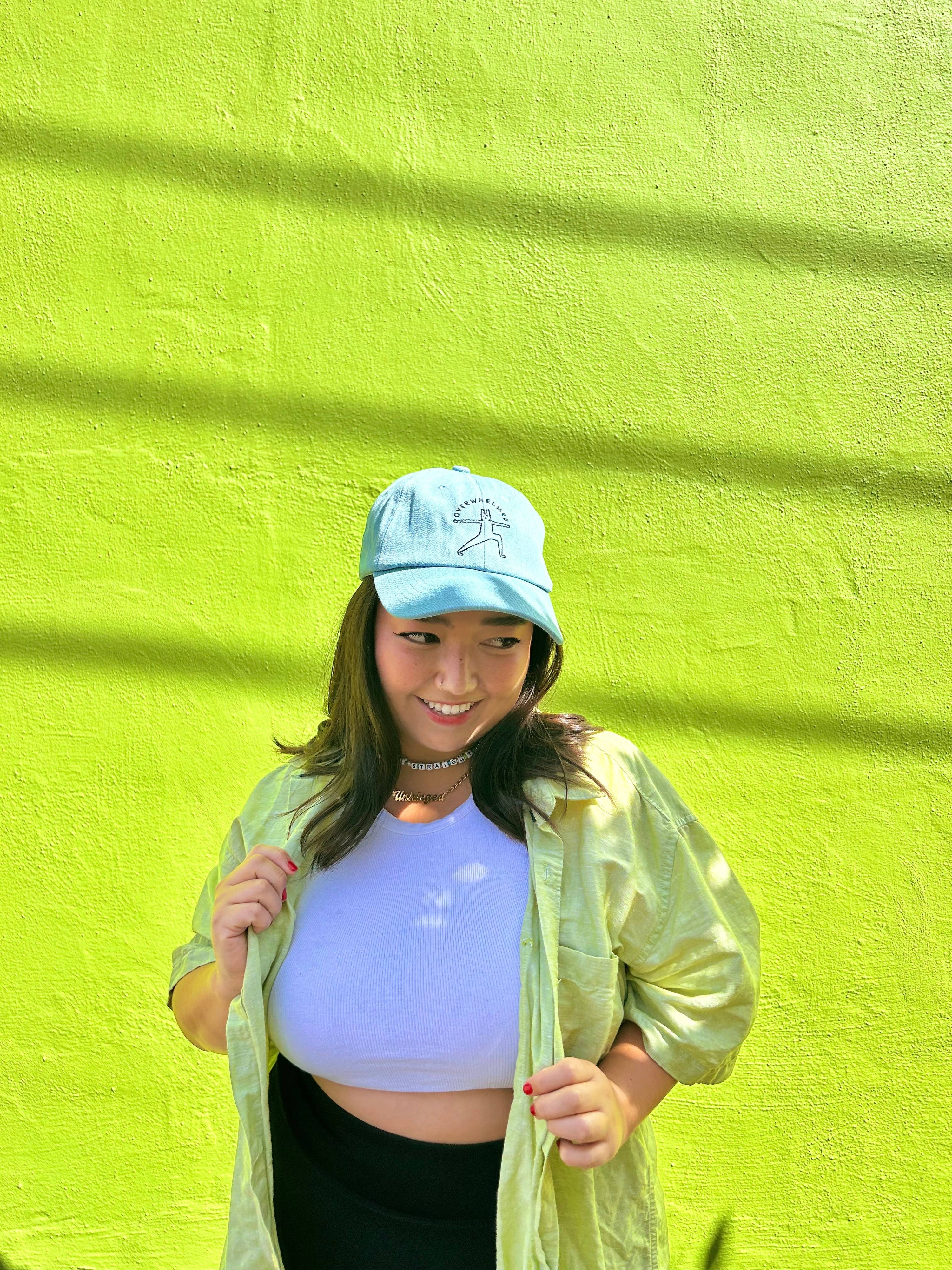 Person wearing a light blue cap and light green jacket against a bright yellow wall