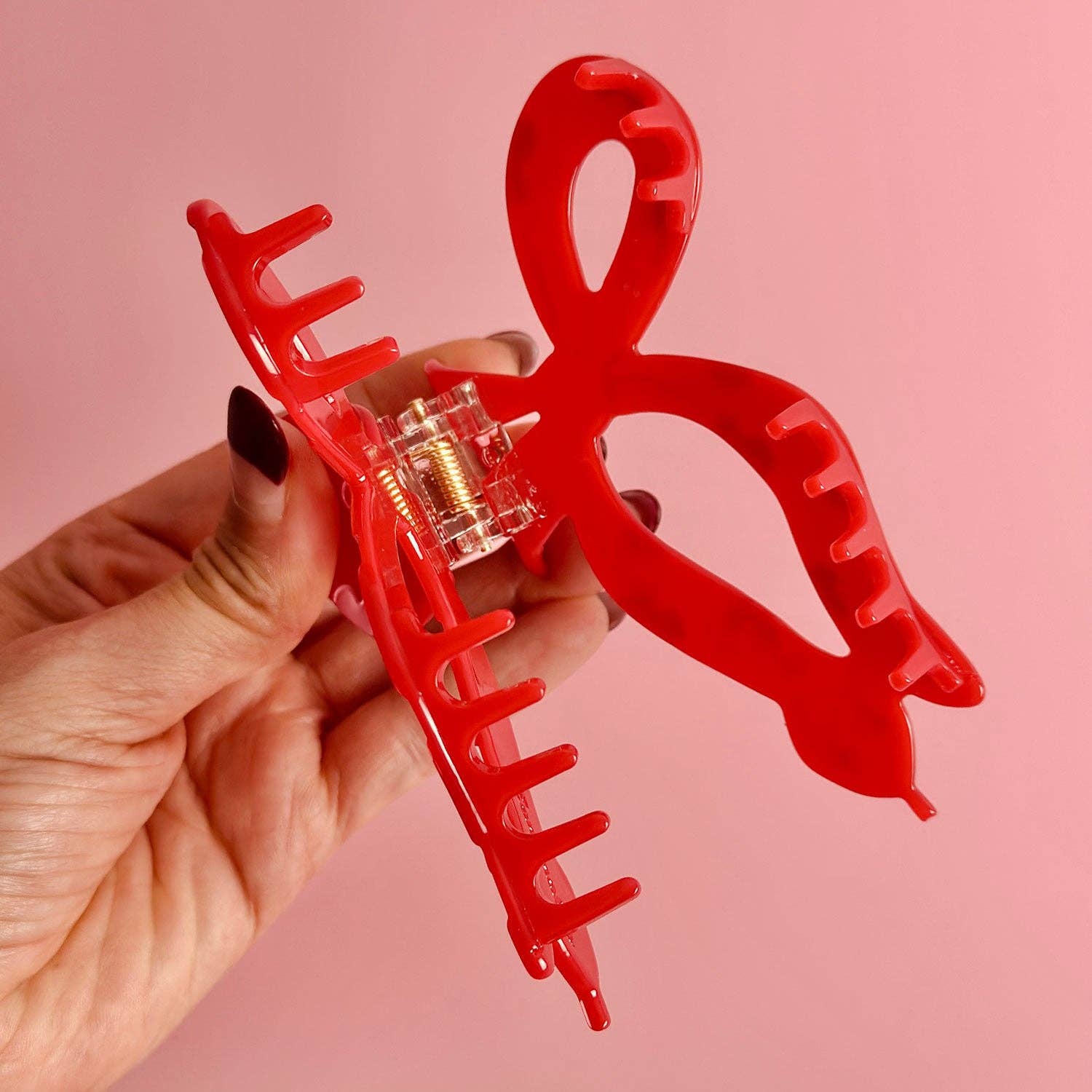 Red hair clip with clear center against a pink background