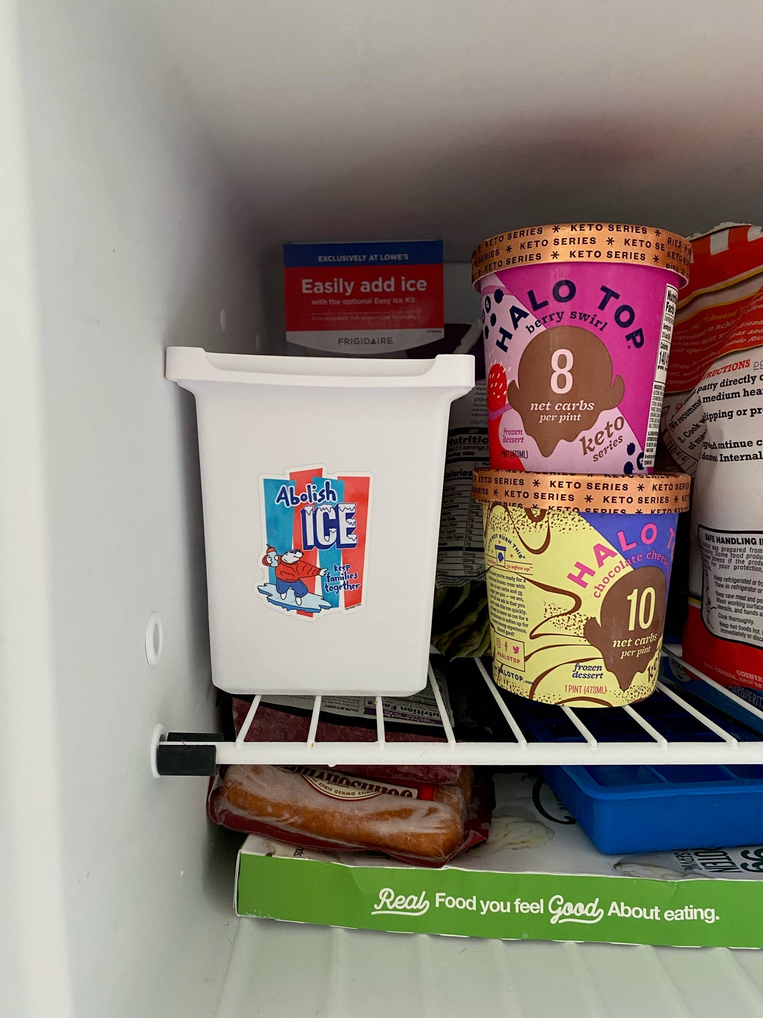 Fridge shelf with containers including a white container labeled 'Abolish ICE' and ice cream