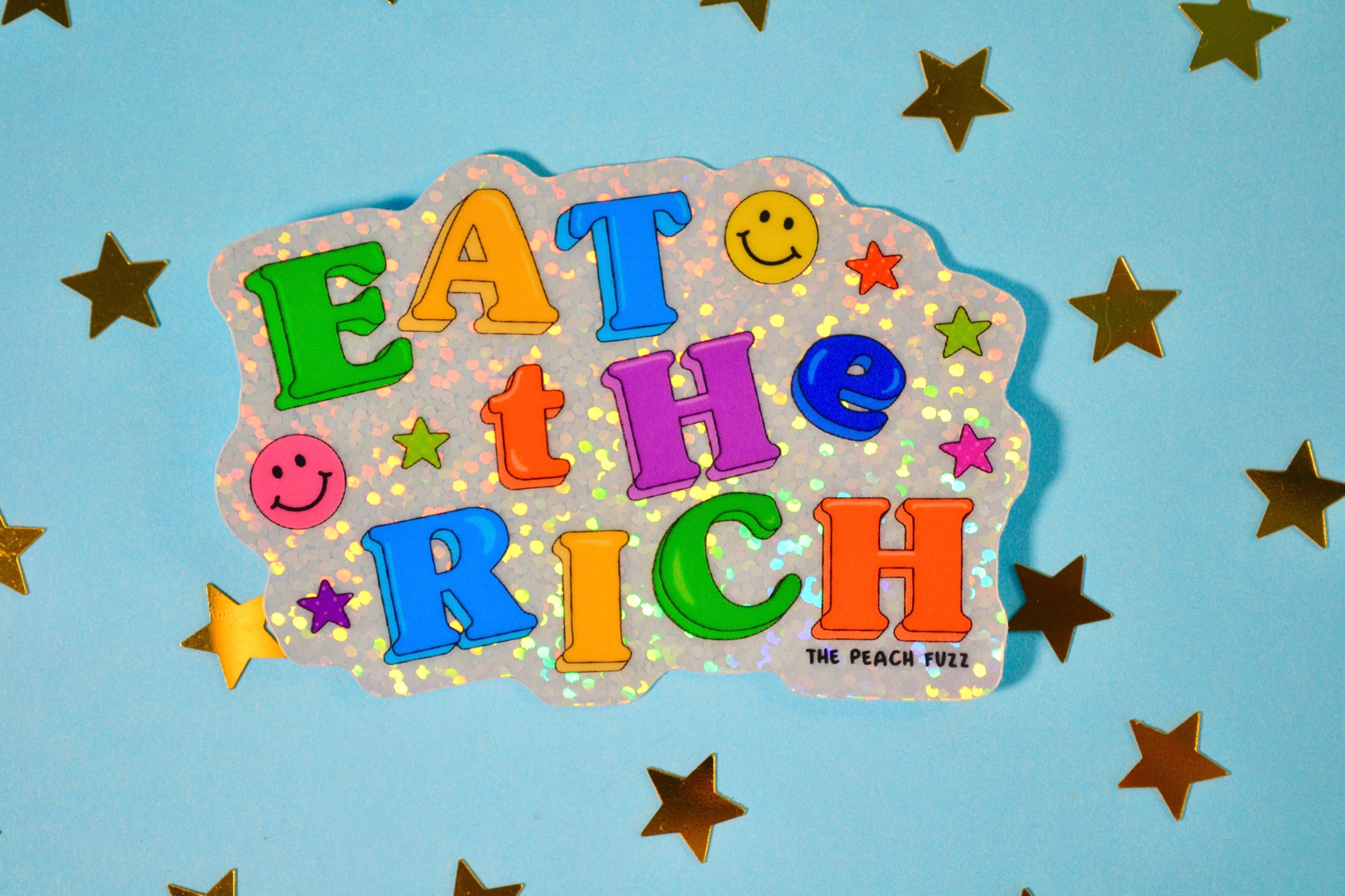 Colorful sign with 'Eat the Rich' text on a blue background with stars