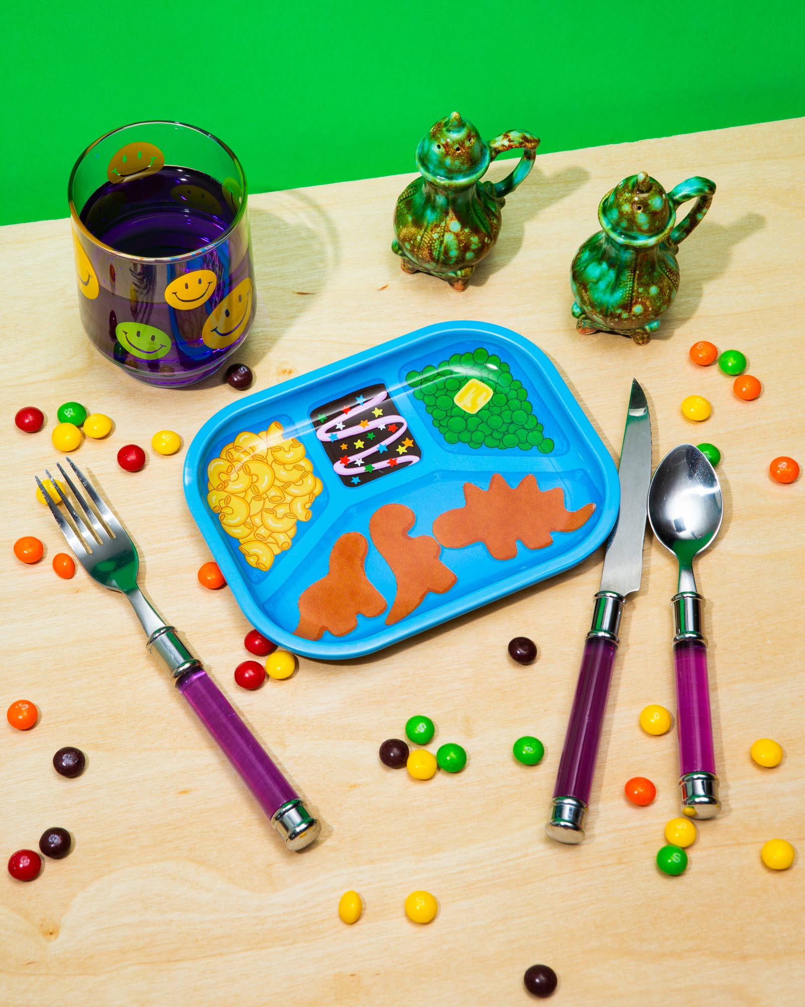Colorful trinket try looking like a retro TV dinner tableware set with a tray, cutlery, and snacks on a wooden surface