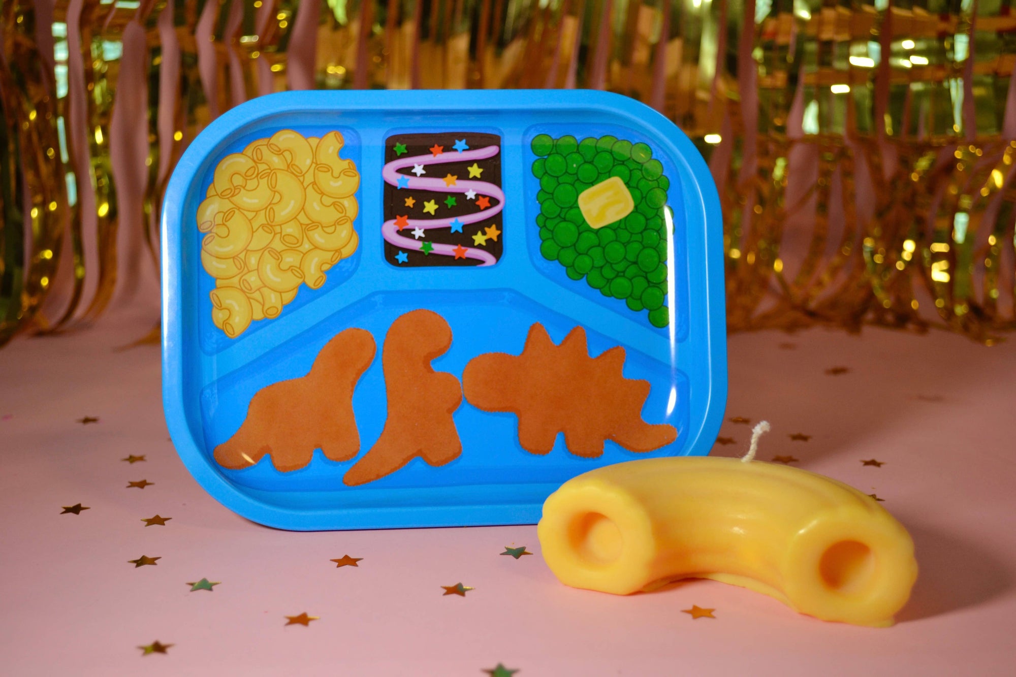 Crafting tray with dinosaur-shaped compartments and a yellow mac and cheese object on a decorative background.