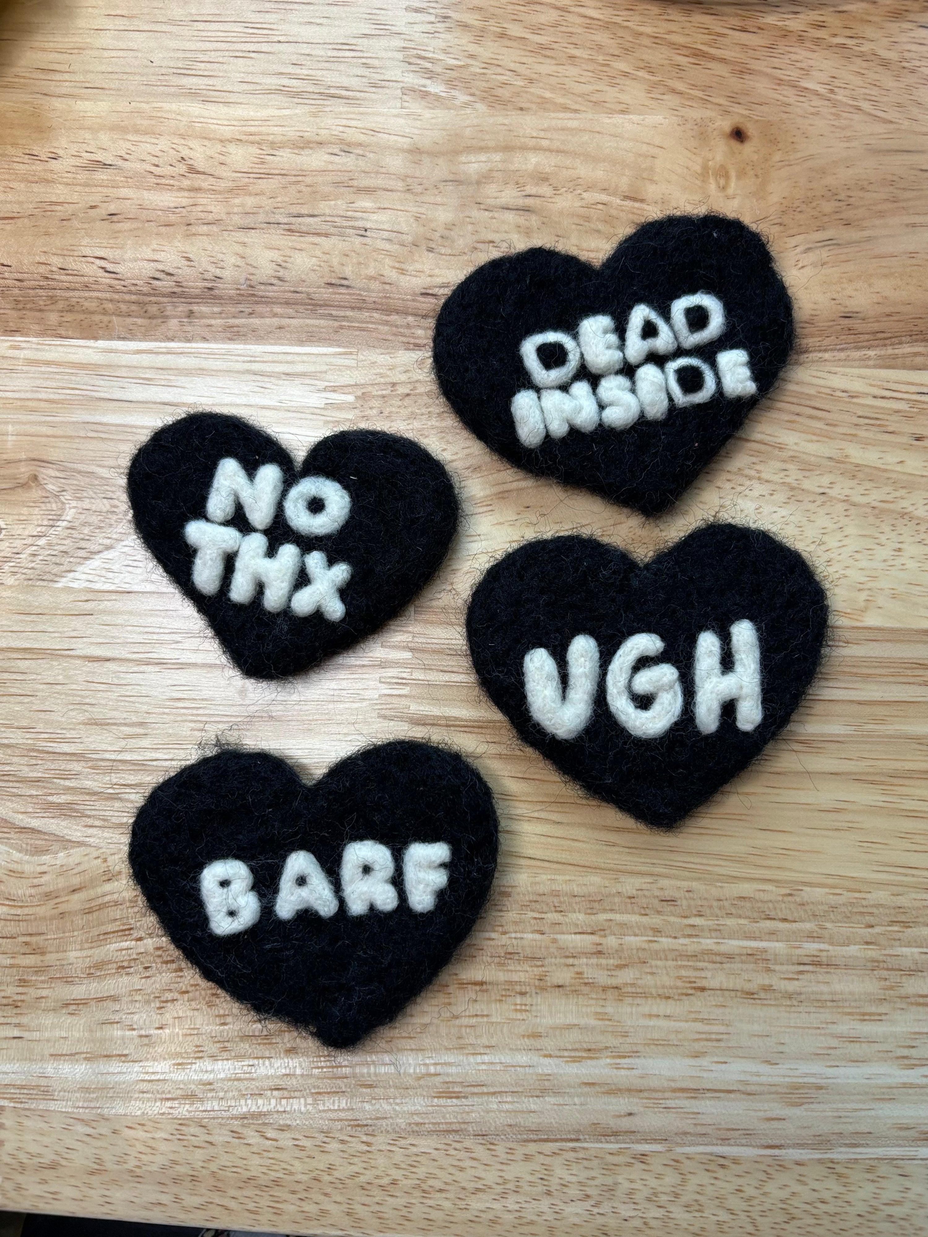 Black heart-shaped wool with white text on a wooden surface