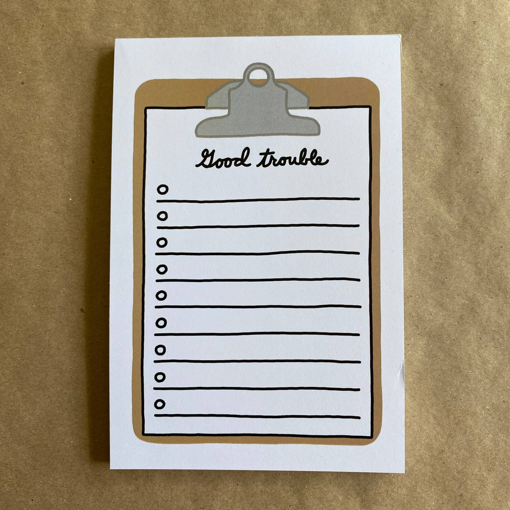 Notebook with 'Good trouble' written on an illustrated clipboard on a brown background