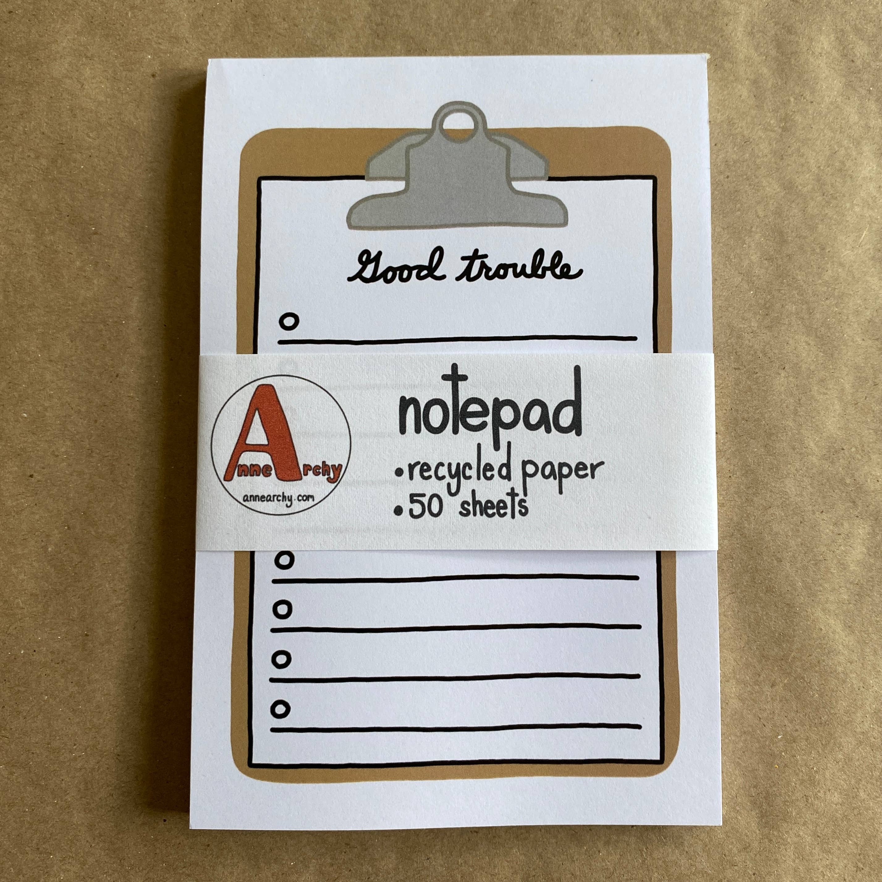 Notepad with a clip and 'Good trouble' text on a brown background