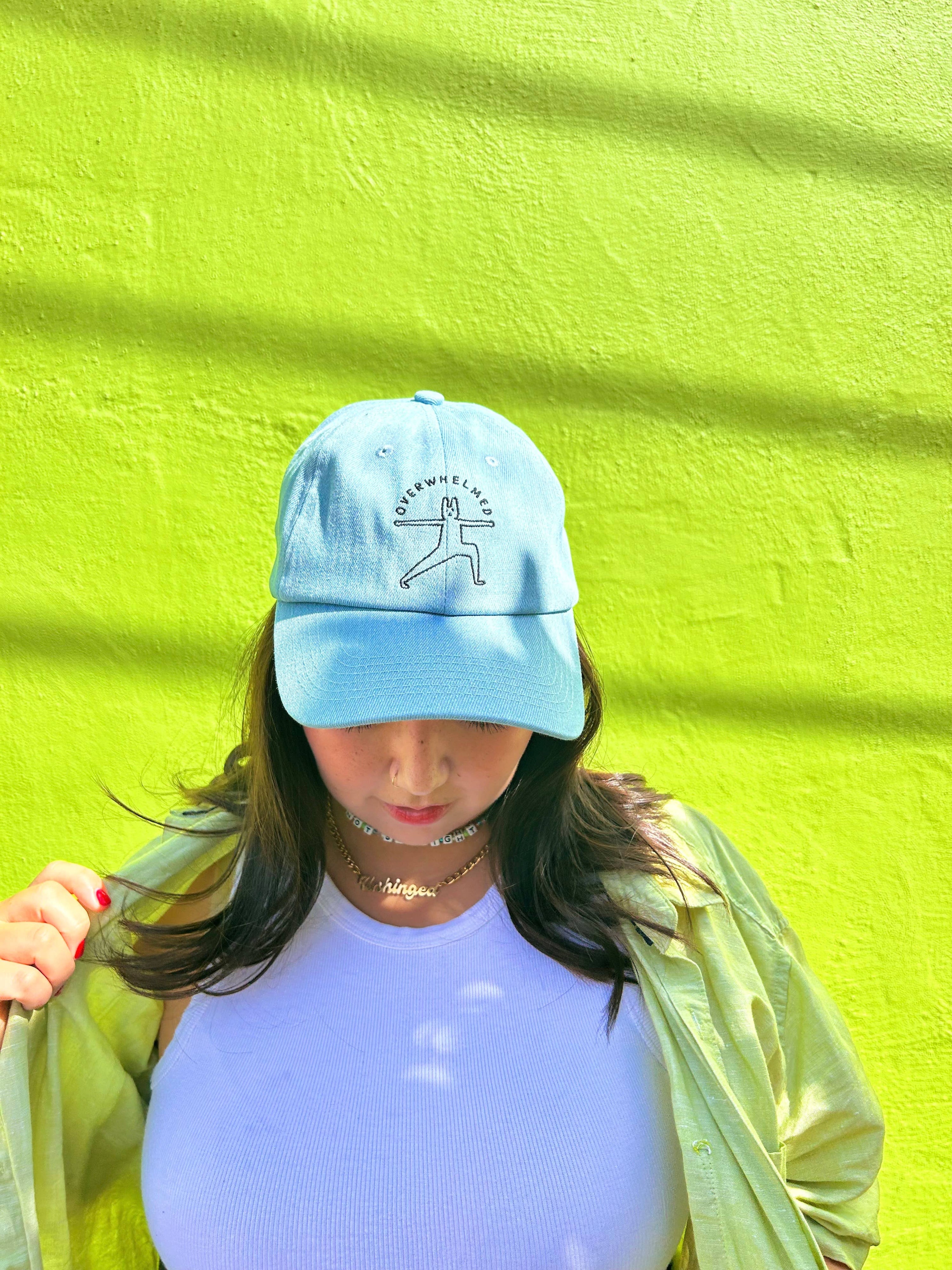 Person wearing a light blue cap with a design against a bright green wall