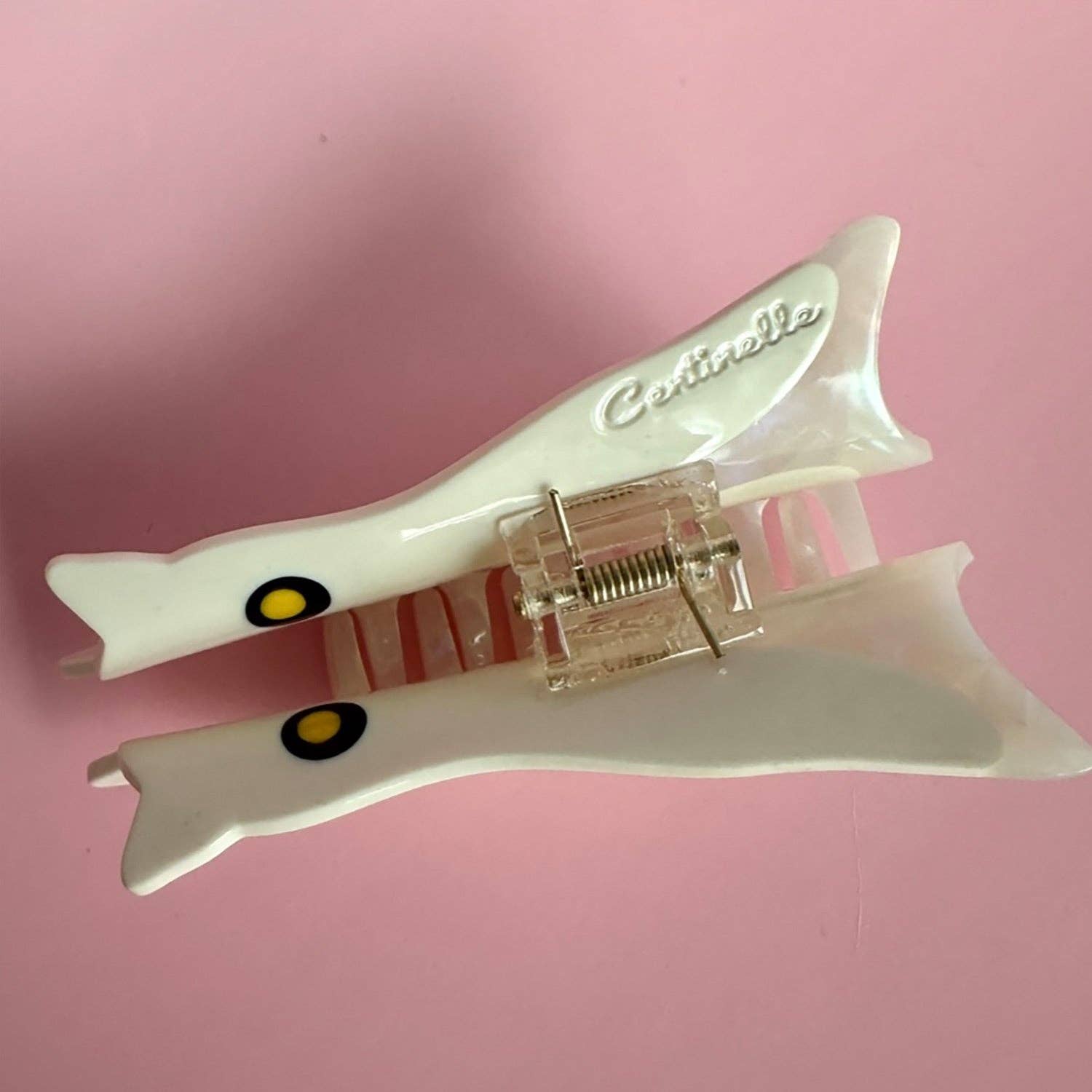 White hair clip with 'Cetrinelle' branding on a pink background