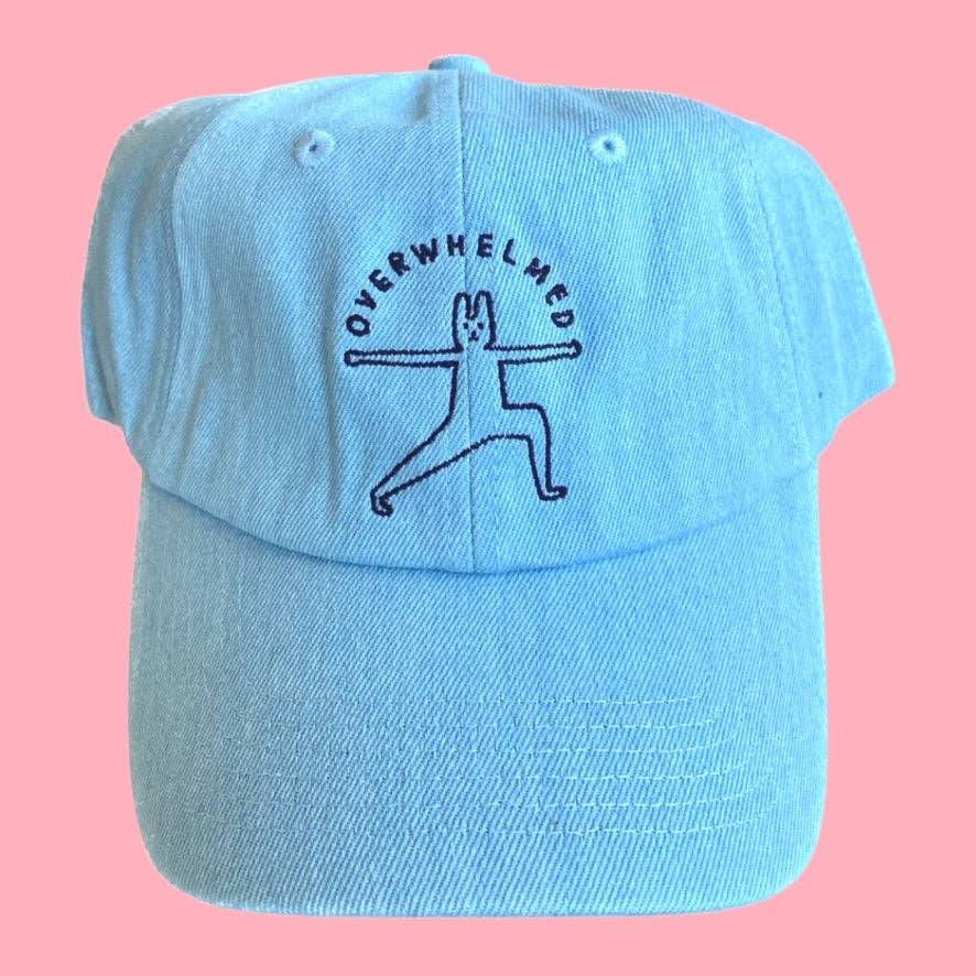 Light blue cap with 'Overwhelmed' yoga pose design on a pink background