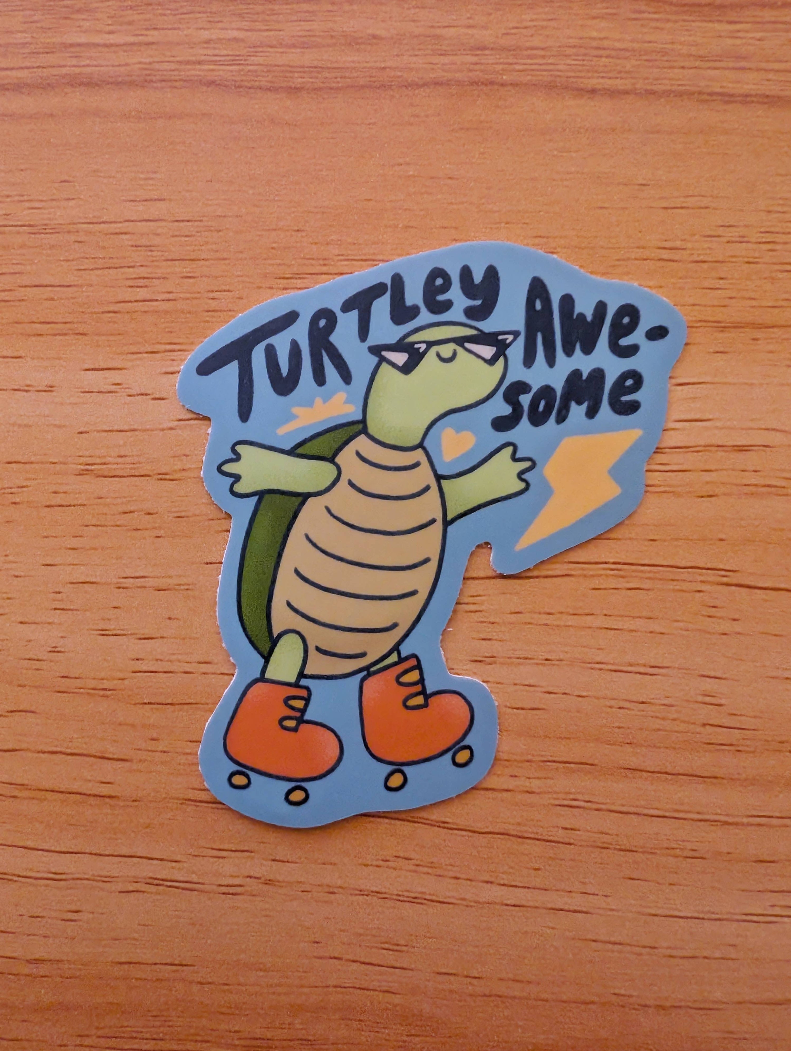 Sticker with a turtle design and 'Turtley Awesome' text on a wooden surface