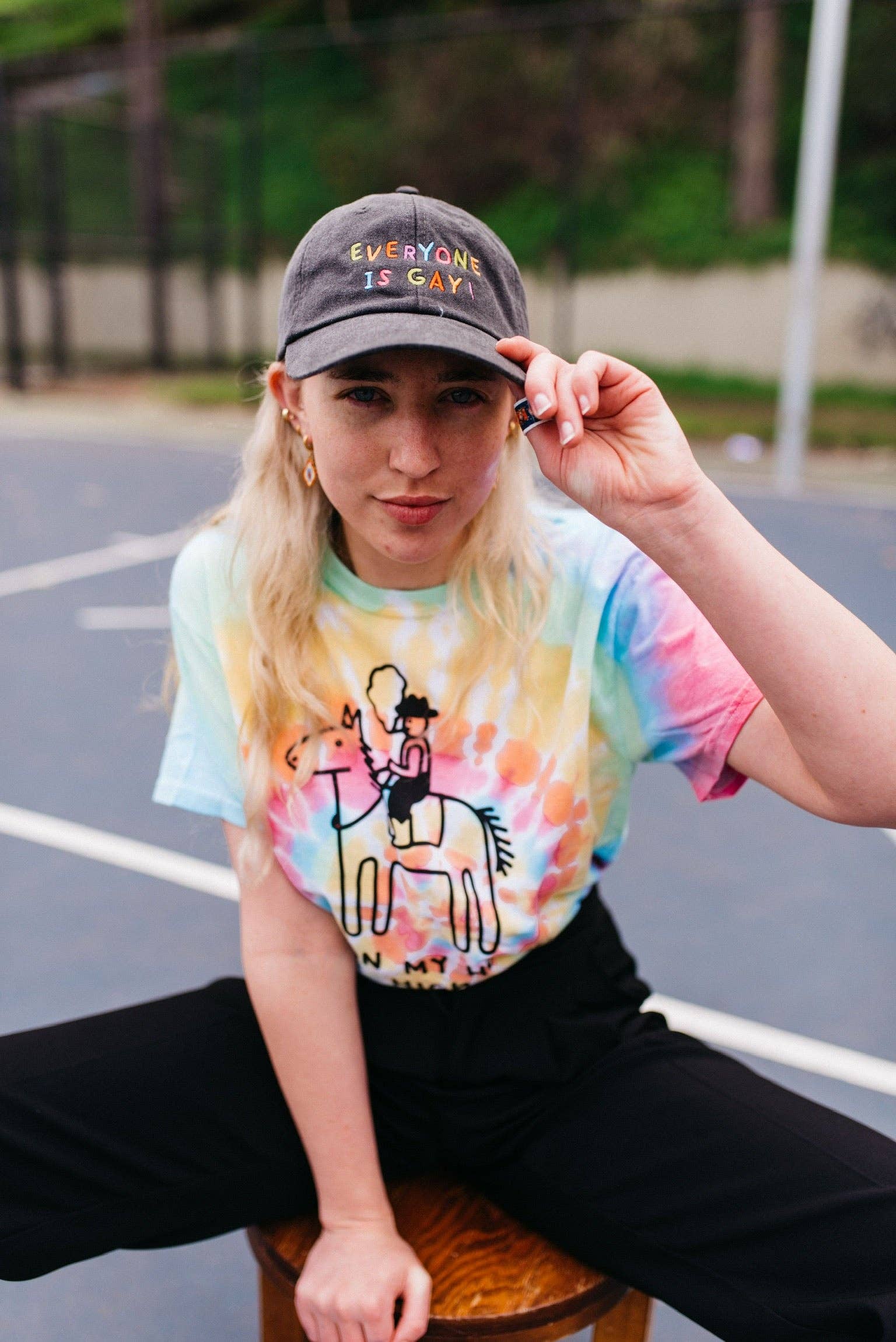 Person wearing a tie-dye shirt and cap on a court
